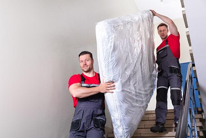 two people carrying a box spring out of a bedroom in Gainesville, VA