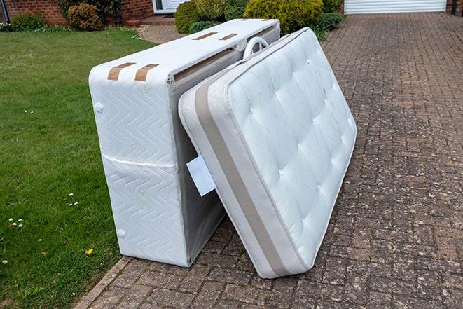 two people carrying a mattress out of a house